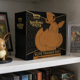 Pokemon Shining Fates Elite Trainer Box im Regal – Lifestyle mit Eevee-Figur und gegradetem Umbreon auf weissem Regal